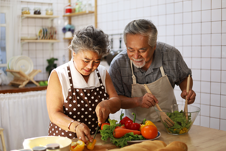 Older adult couple making a salad in their kitchen