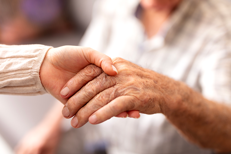 A patient holding the hand of a caregiver or nurse for emotional support.